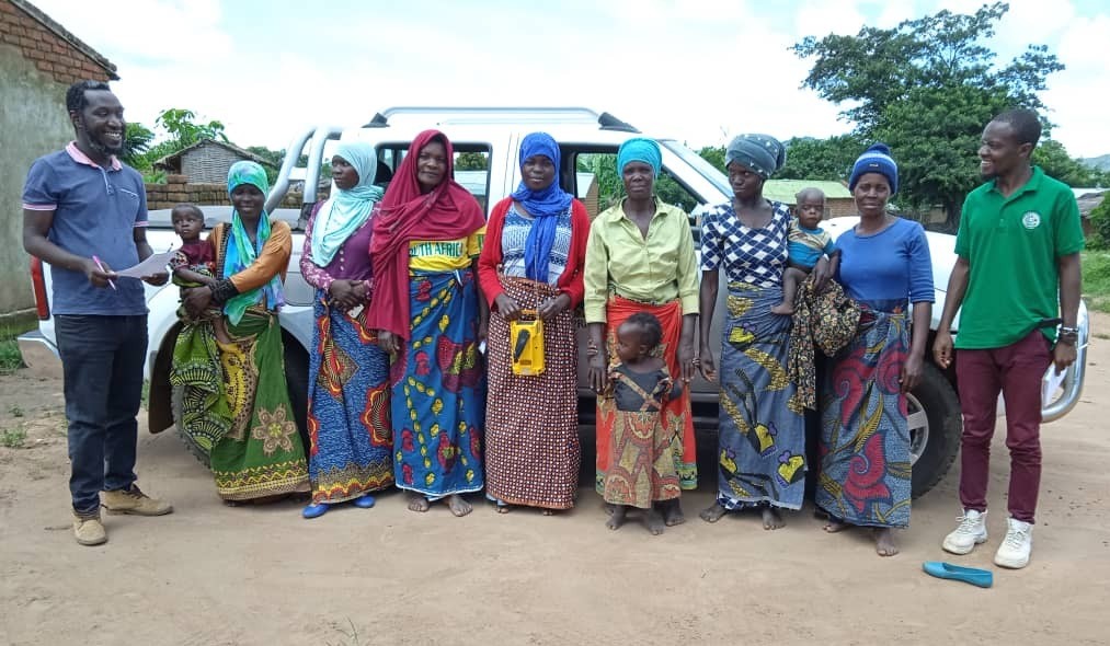 Group of women standing with 3 small children, flanked by 1 man on either side