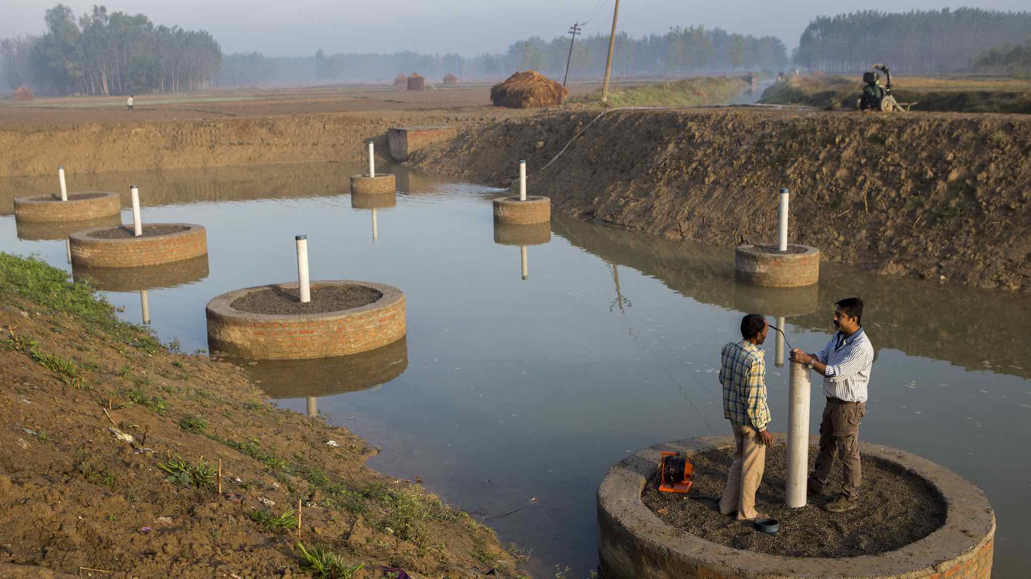 Two men stand on a platform to test groundwater