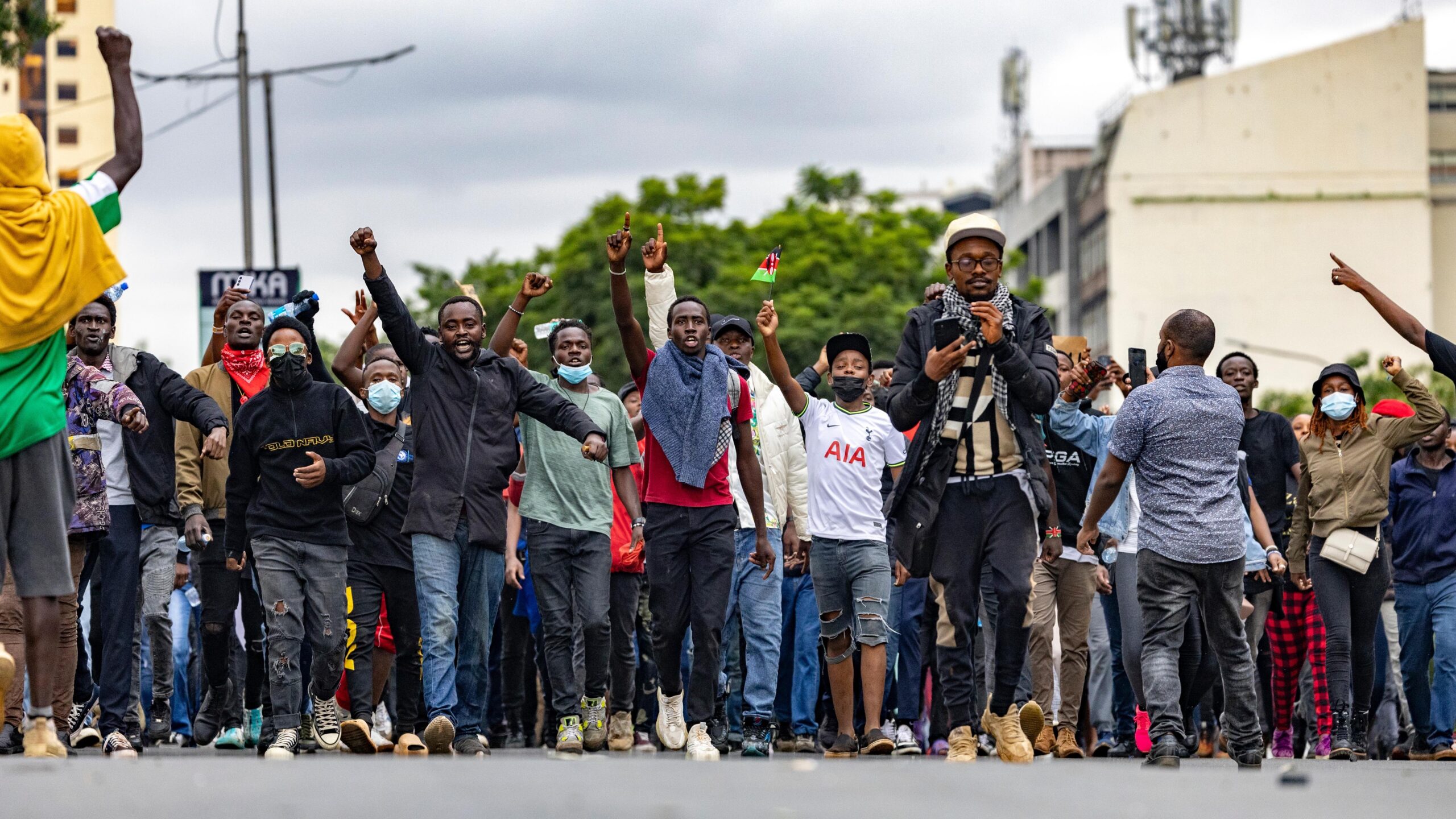 Line of protestors marching in the street, some with fists raised