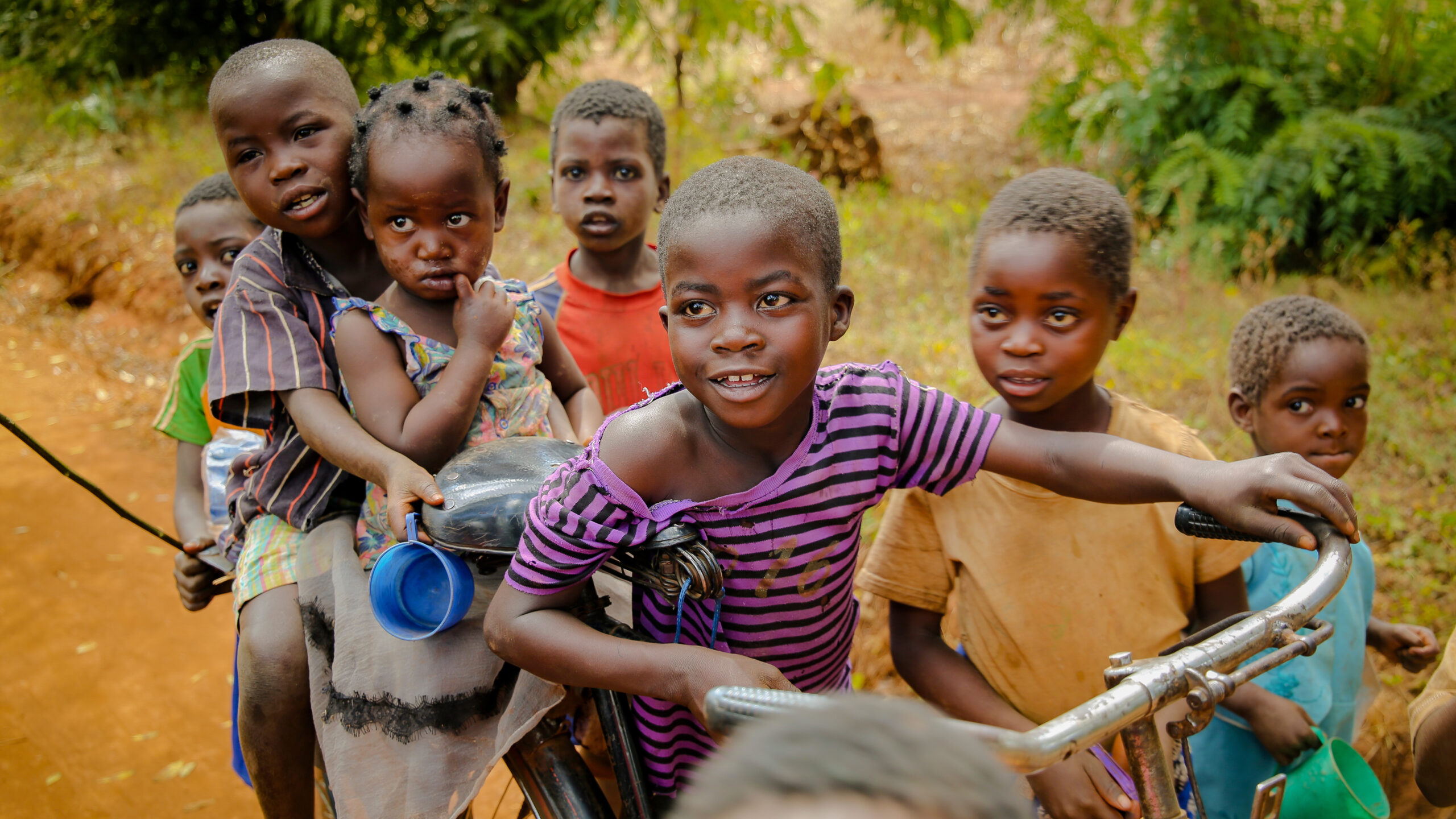 Seven boys and girls, some on a bicycle