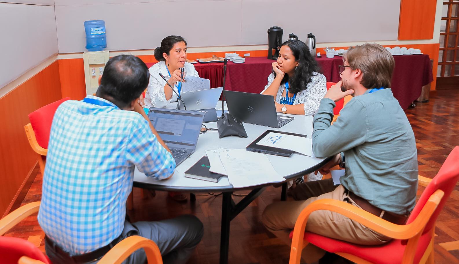 Two men, two women sit around table in discussion