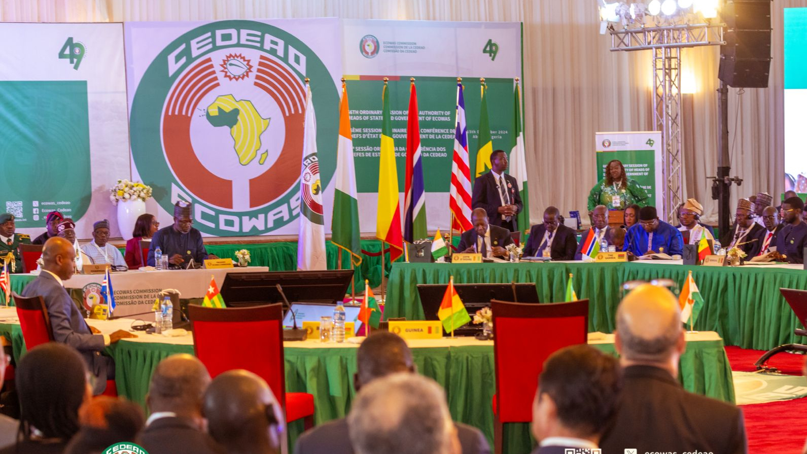 Delegates sitting at tables in front of ECOWAS banner